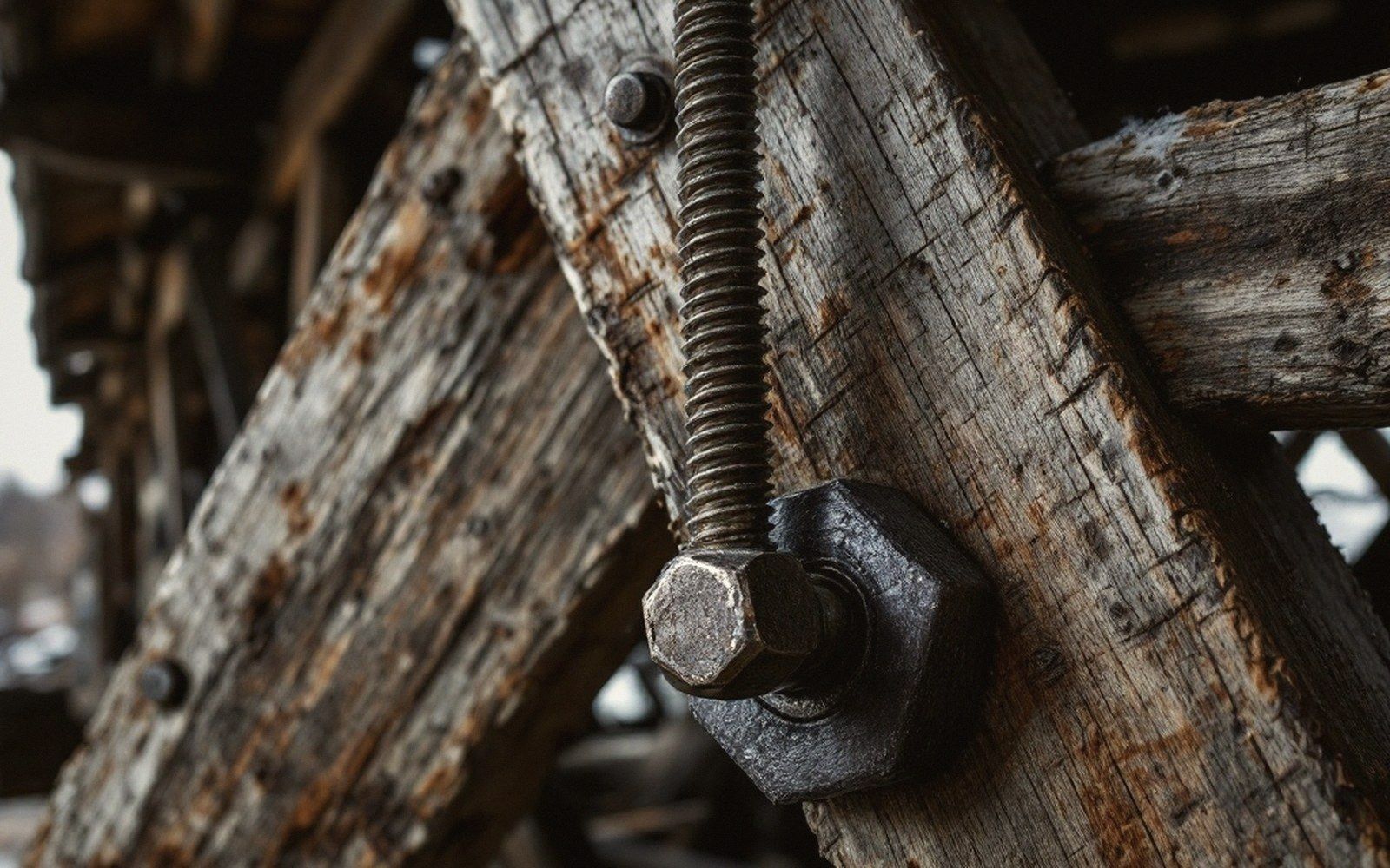 An iron tension rod and its nut bearing against weathered timber